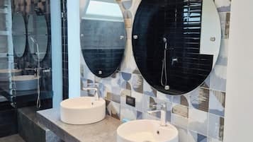 A modern bathroom with two round mirrors, two sinks, and a tiled backsplash.
