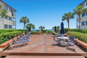 Eine Terrasse mit Liegestühlen und Sonnenschirmen mit Blick auf einen Strand und den Ozean.