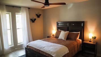 A bedroom with a bed, two bedside tables, a ceiling fan, and a window with curtains.