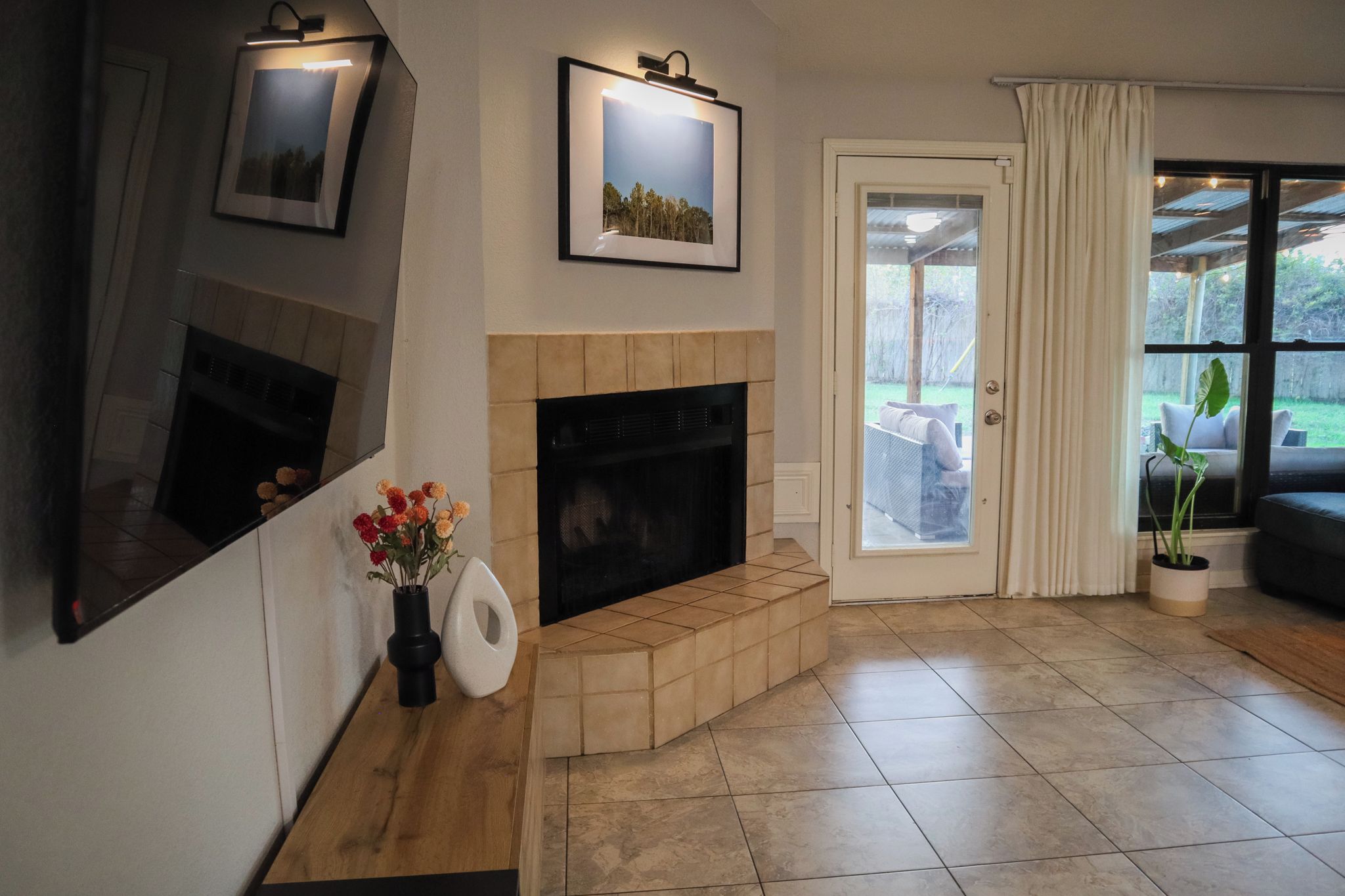 A living room with a fireplace, a large mirror, and a view through a glass door to an outdoor area.