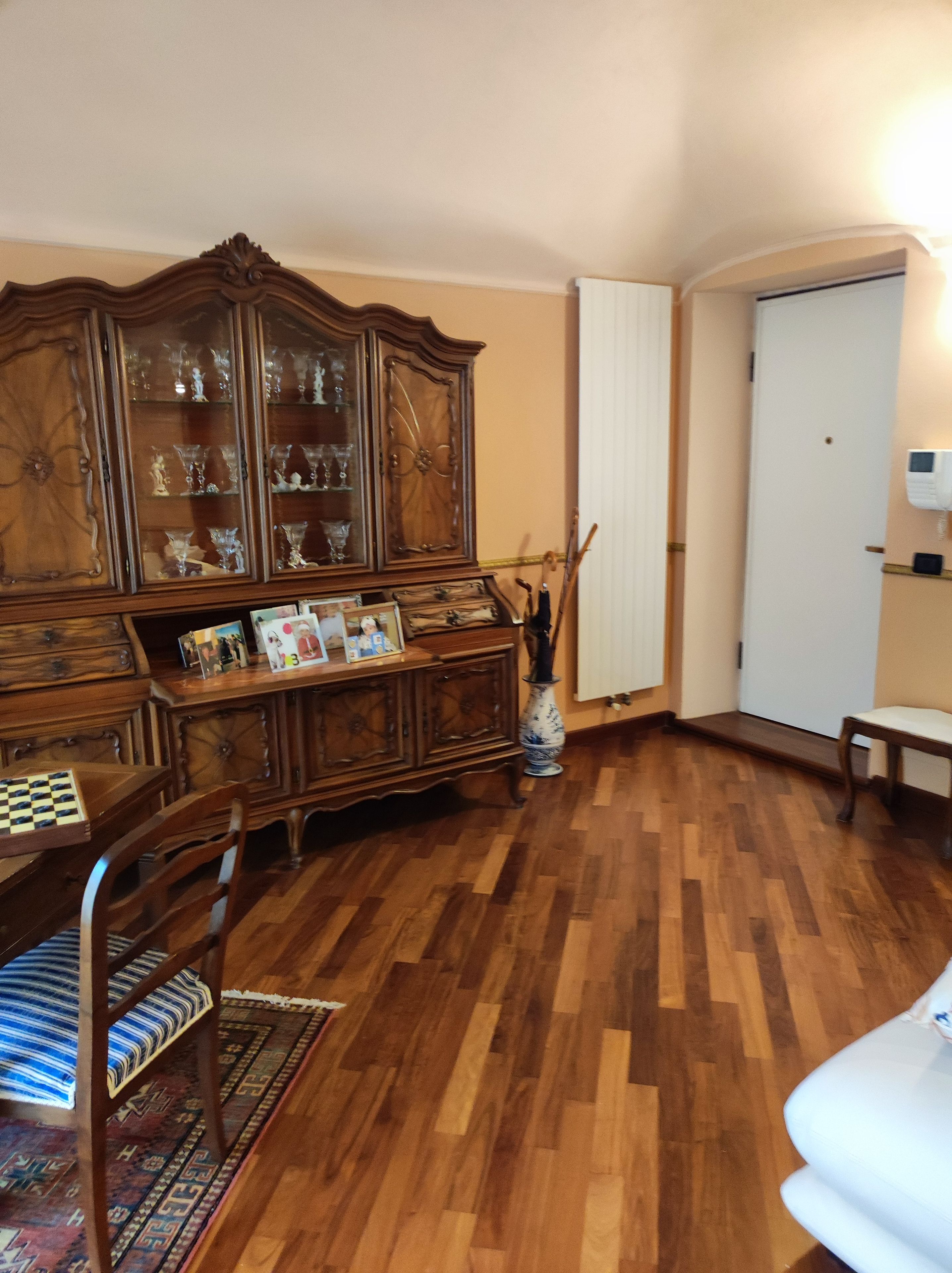 A room with a wooden cabinet, a chessboard, a patterned rug, and a white bench.