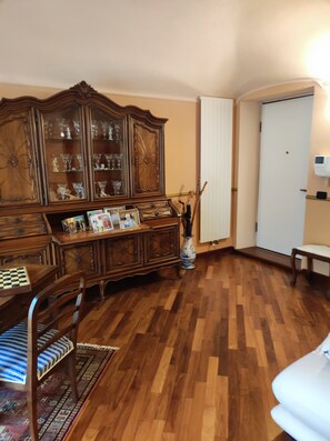 A room with a wooden cabinet, a chessboard, a patterned rug, and a white bench. - MAISON PLATONE PRESTIGE (Alessandria)