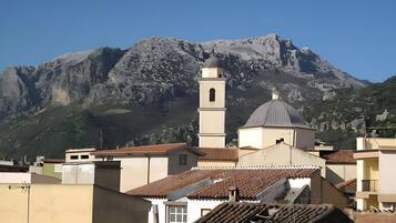 A building with a bell tower and a dome, surrounded by residential buildings and a mountain in the background.