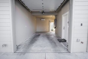 Un garage con pavimento in cemento, una ventola a soffitto e una porta che dà su un corridoio.