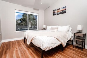 Una camera da letto con un'ampia finestra, un letto, comodini e un'opera d'arte appesa al muro.