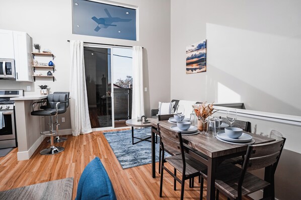 A modern kitchen with a microwave, oven, and a dining area with a table set for two. - Hybrid King Bed•Pets Ok•Walkers Paradise•500mbps (Reno)