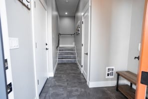 A hallway with a staircase leading to an upper floor, white walls, and a bench on the right. - Hybrid King Bed•Pets Ok•Walkers Paradise•500mbps (Reno)