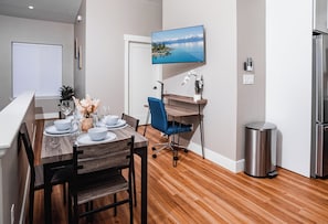 A modern kitchen with a built-in oven, a stainless steel refrigerator, and a dining area with a wooden table and chairs. - Hybrid King Bed•Pets Ok•Walkers Paradise•500mbps (Reno)