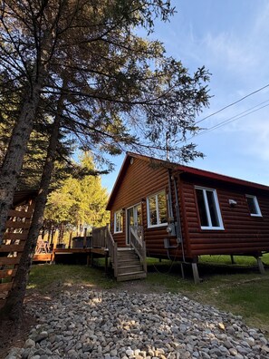 A wooden cabin with a porch and a staircase leading to the entrance.
