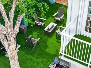 Ein Garten mit Baum, weißem Zaun und Gartenmöbeln.