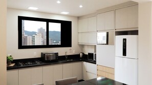 Eine moderne Küche mit integriertem Mikrowellenherd, Toaster und Kühlschrank, ein Fenster mit Blick auf die Stadt und eine kleine Essecke.