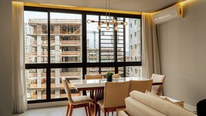 Ein modernes Wohnzimmer mit großem Fenster, einem Esstisch und einer Couch.