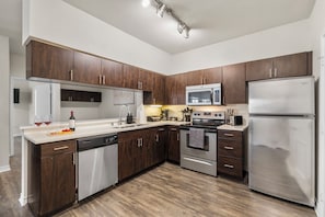 A modern kitchen with dark wood cabinets, stainless steel appliances, and a white countertop. - Charming 2-bedroom apartment with AC in Dallas (Dallas)