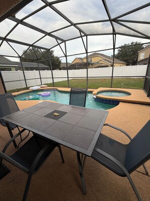 A covered outdoor area with a pool, a table, and chairs. - Elegant Renovated Home with Private Fenced Pool and 4 Spacious bedrooms (Davenport)