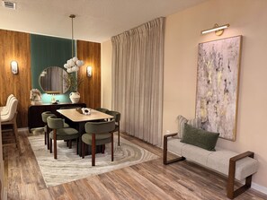 A modern dining area with a wooden dining table, green upholstered chairs, a decorative vase, and a large abstract painting on the wall. - Elegant Renovated Home with Private Fenced Pool and 4 Spacious bedrooms (Davenport)