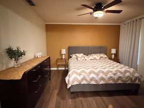 A bedroom with a bed, nightstands, a ceiling fan, a dresser, and a plant. - Elegant Renovated Home with Private Fenced Pool and 4 Spacious bedrooms (Davenport)