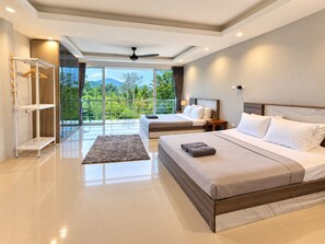 A modern hotel room with a large bed, a smaller bed, a balcony with a view, and a ceiling fan. - 4 bedroom & bathroom pool villa, with golf view. Only 7km to Patong (Tambon Kathu)