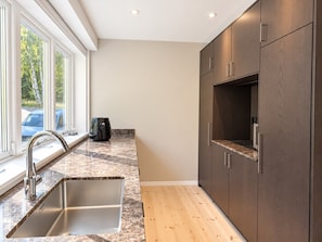 A modern kitchen with a built-in sink, dark wooden cabinets, and a window with a view of the outside. - Unique event venue—pool, gym, and sauna (Stockholm)