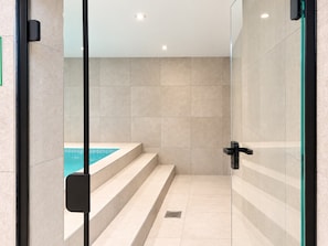 A modern bathroom with a glass shower enclosure, a built-in bathtub, and a tiled floor. - Unique event venue—pool, gym, and sauna (Stockholm)