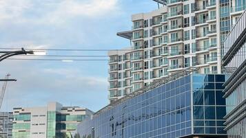 A modern multi-story building with a glass facade, surrounded by palm trees and other commercial buildings.