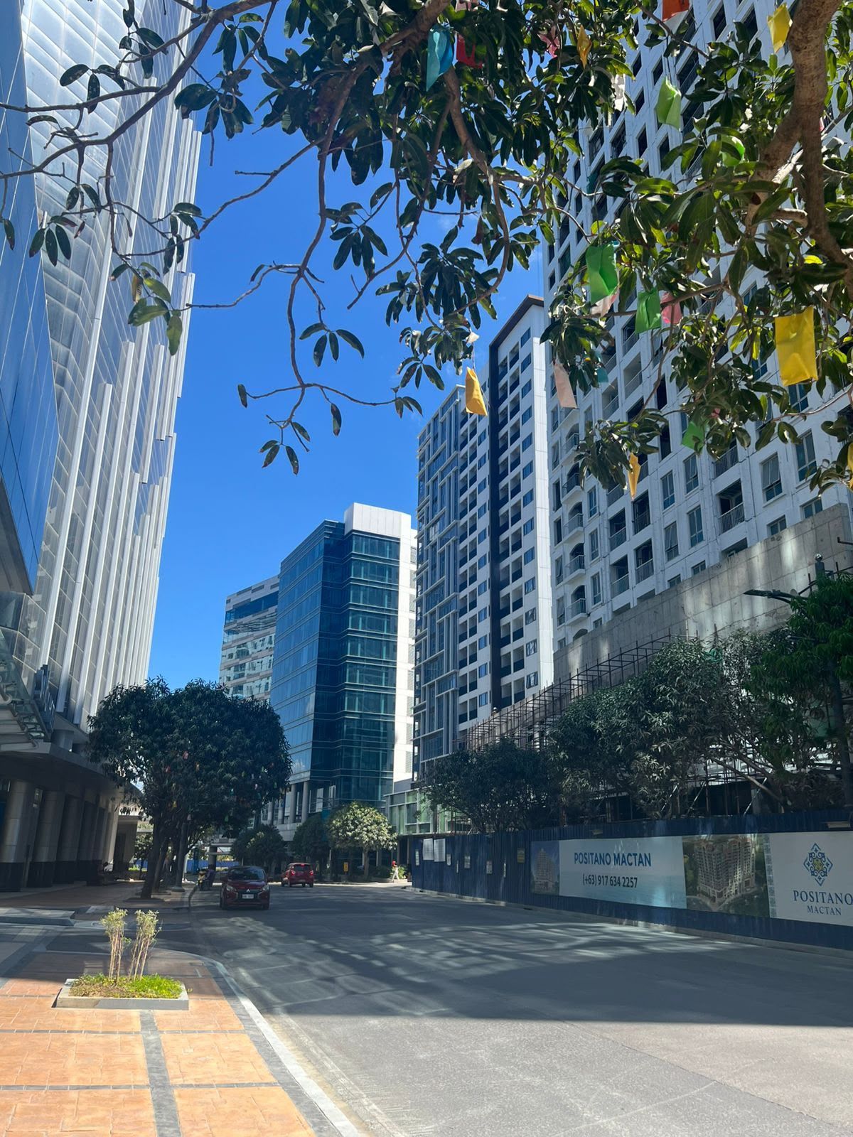 Une rue de la ville, avec des bâtiments modernes, un ciel dégagé et une enseigne indiquant « Positano Mactan ».