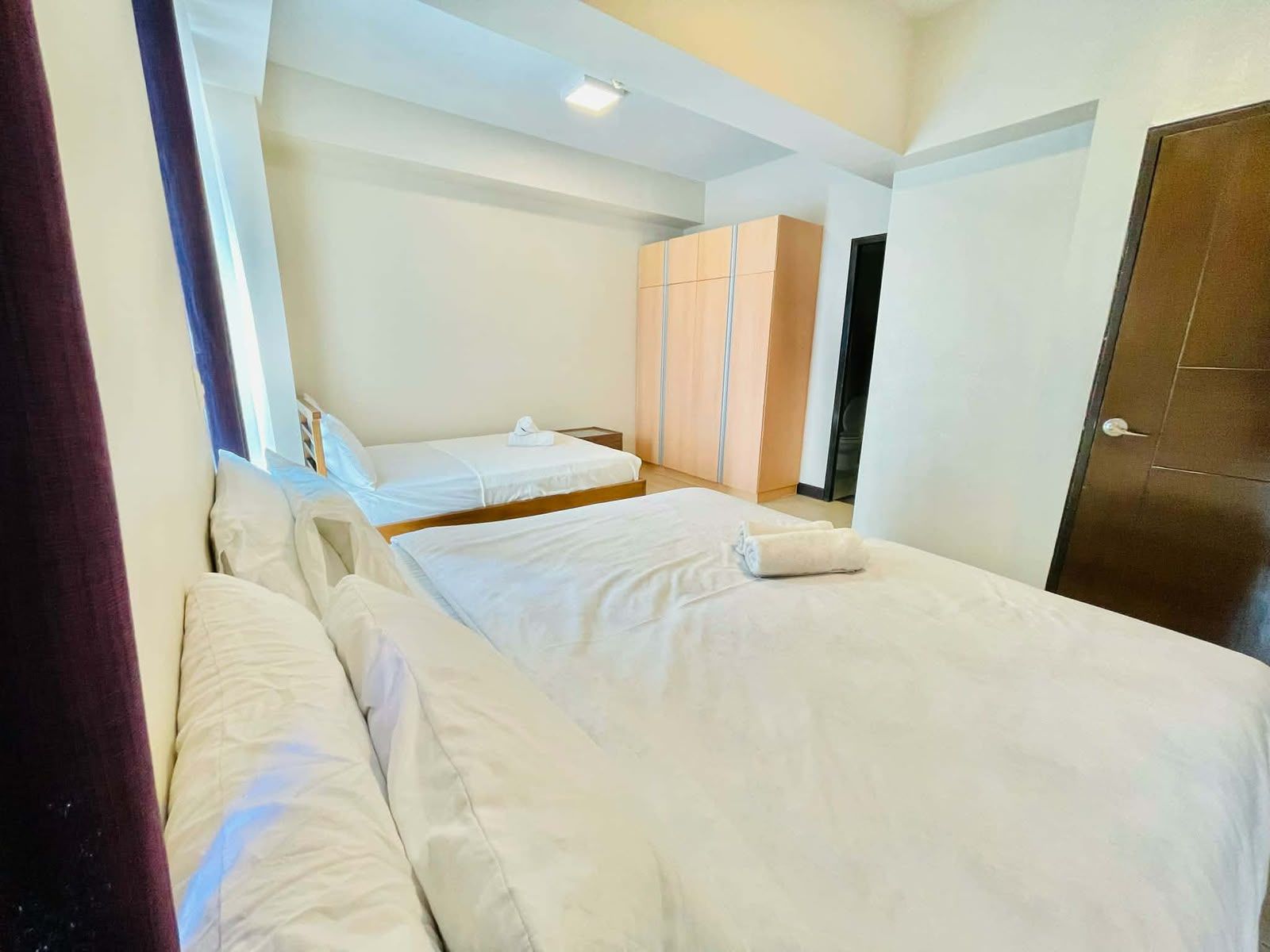 Une chambre d’hôtel avec deux lits, une armoire et une porte.