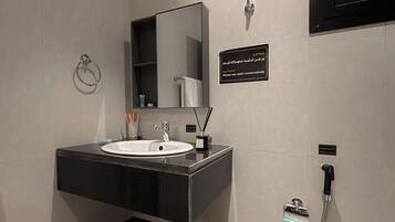 A modern bathroom with a sink, mirror, and a shower area.