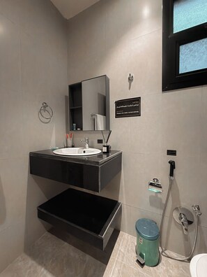 Un baño moderno con lavamanos, espejo y zona de ducha.