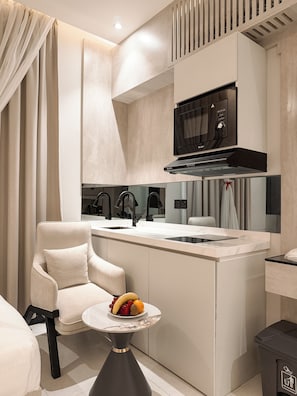 Una cocina moderna con microondas integrado, un fregadero y un comedor con una silla y una mesa pequeña con fruta.