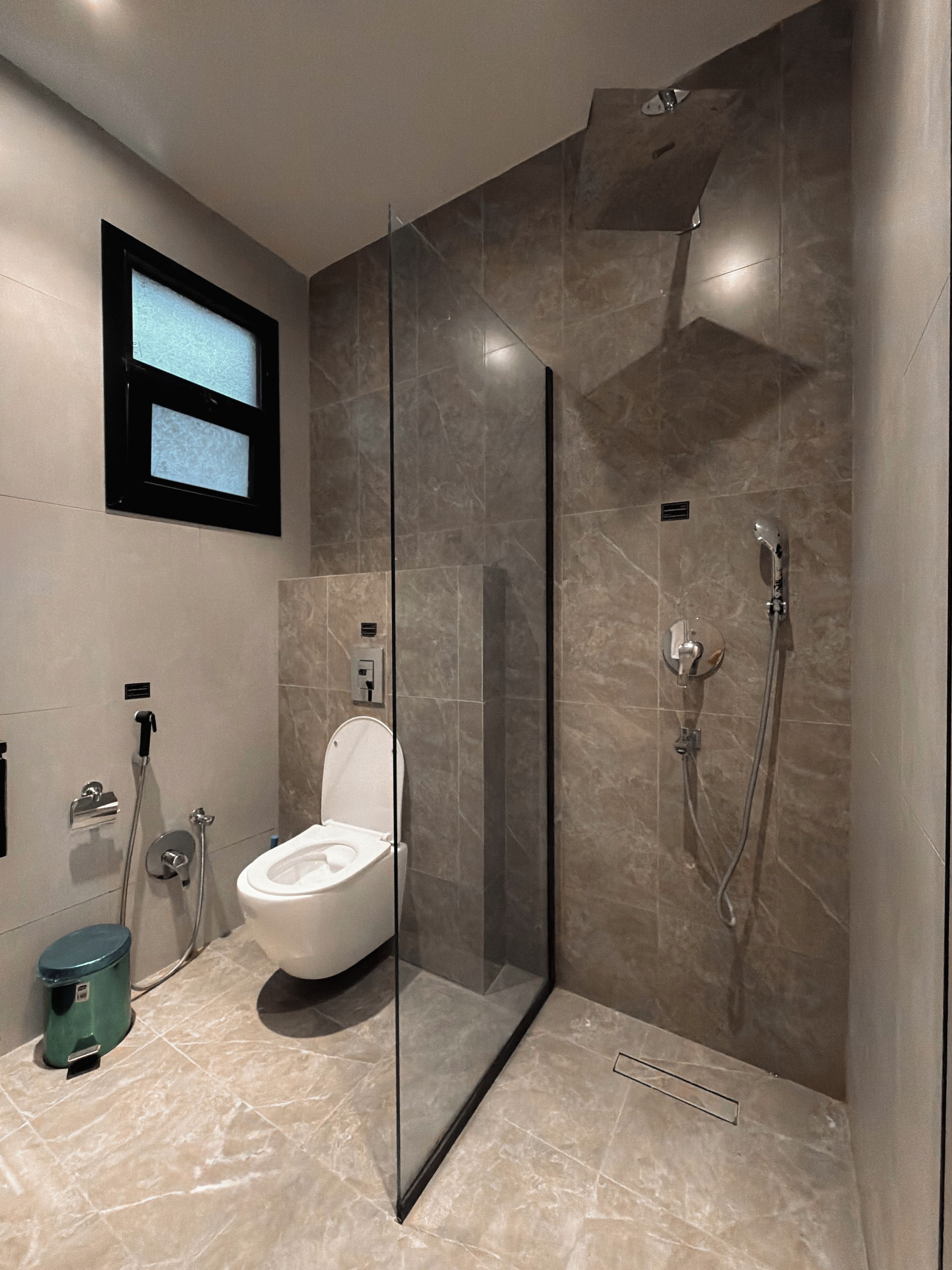 A modern bathroom with a glass-enclosed shower, a toilet, and a bidet.