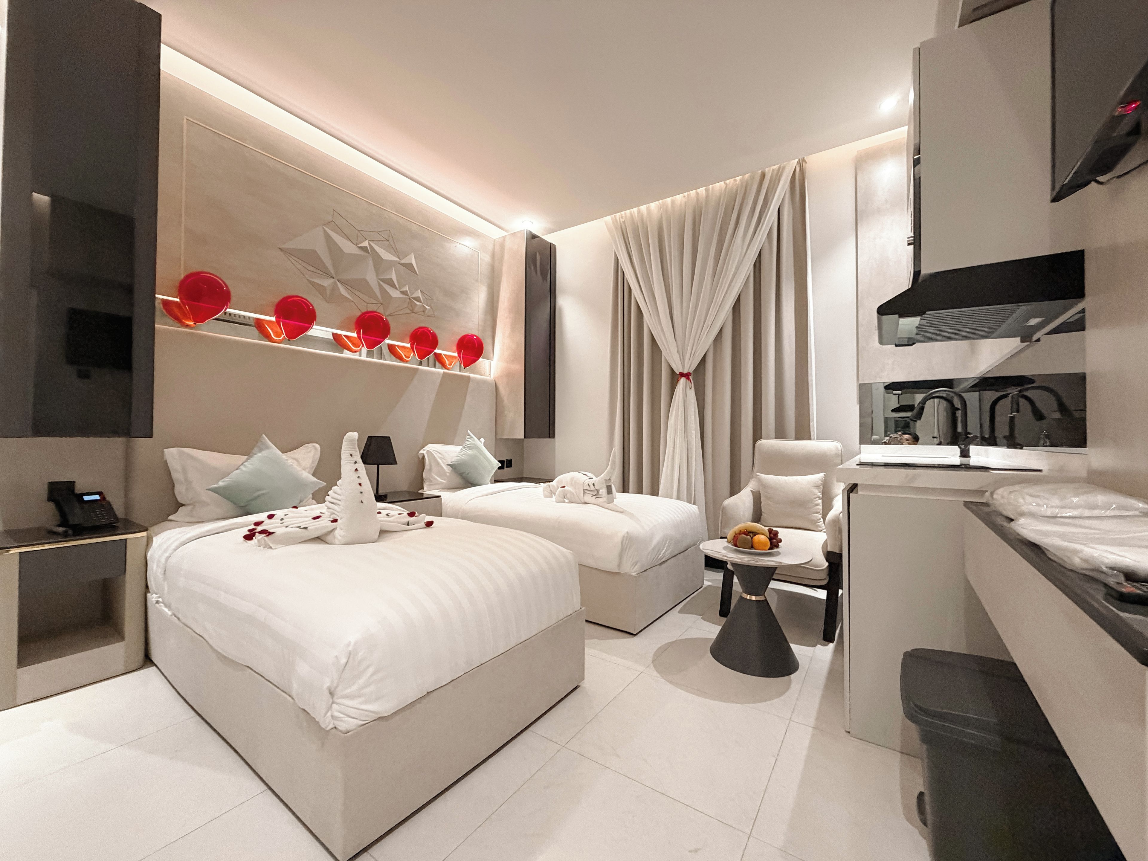 A modern hotel room with a large bed, two smaller beds, a desk, and a bathroom.