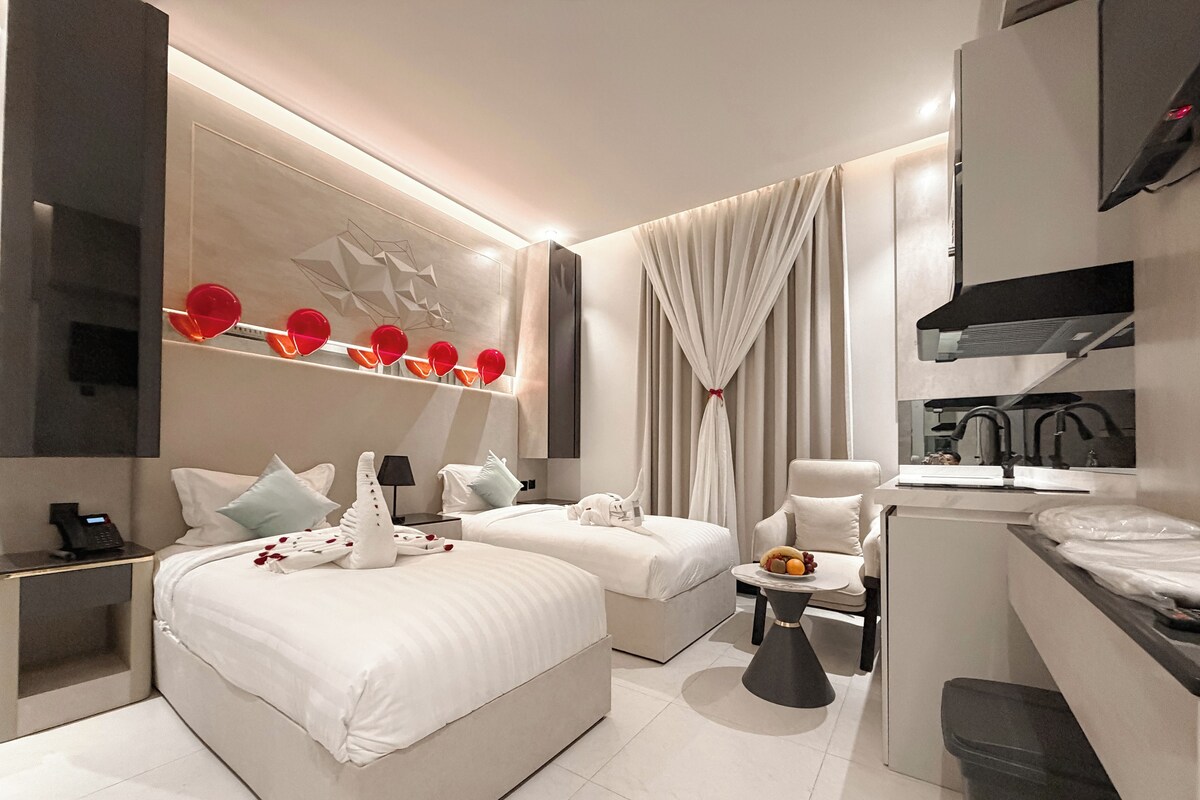 Ein modernes Hotelzimmer mit einem großen Bett, zwei Einzelbetten, einem Schreibtisch und einem Badezimmer.