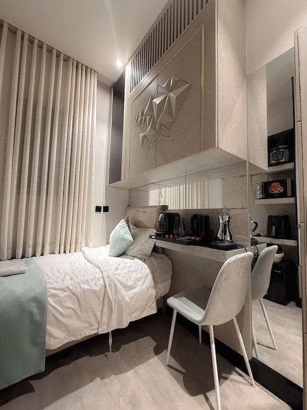 A modern bedroom with a bed, a desk, and a chair. There is a coffee machine and a microwave on the desk. - Mayyoun  serviced apartments (Riyadh)