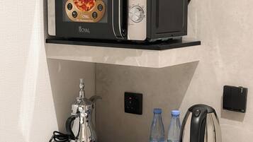 A microwave oven with a pizza image on the front, a coffee maker, two water bottles, and a kettle on a countertop.