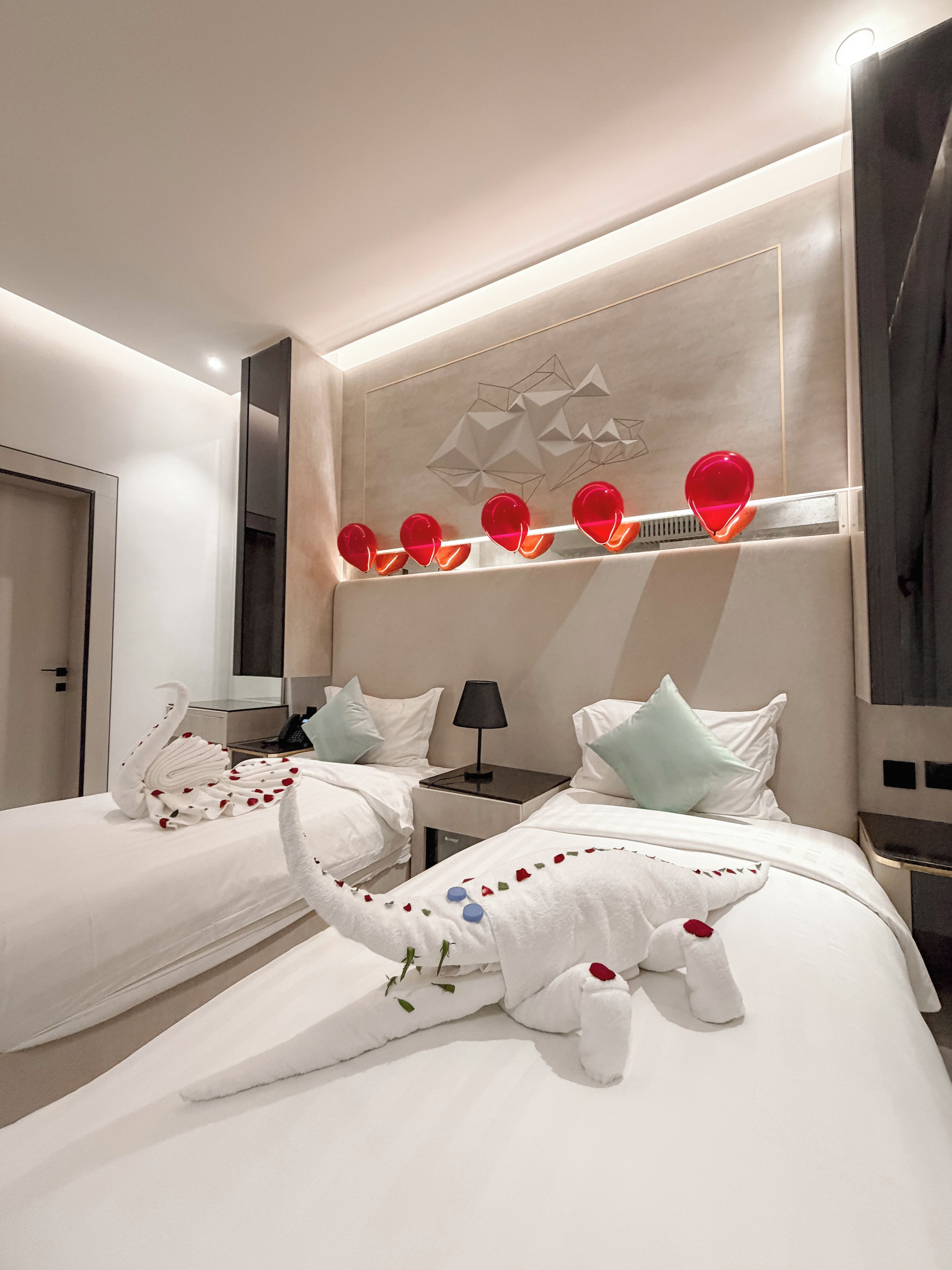 Habitación de hotel con dos camas, una lámpara fijada a la pared y un panel decorativo.