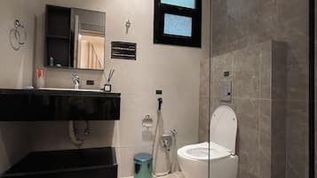 Ein modernes Badezimmer mit einer Duschkabine, einer Toilette und einem Waschtisch mit Spiegel.