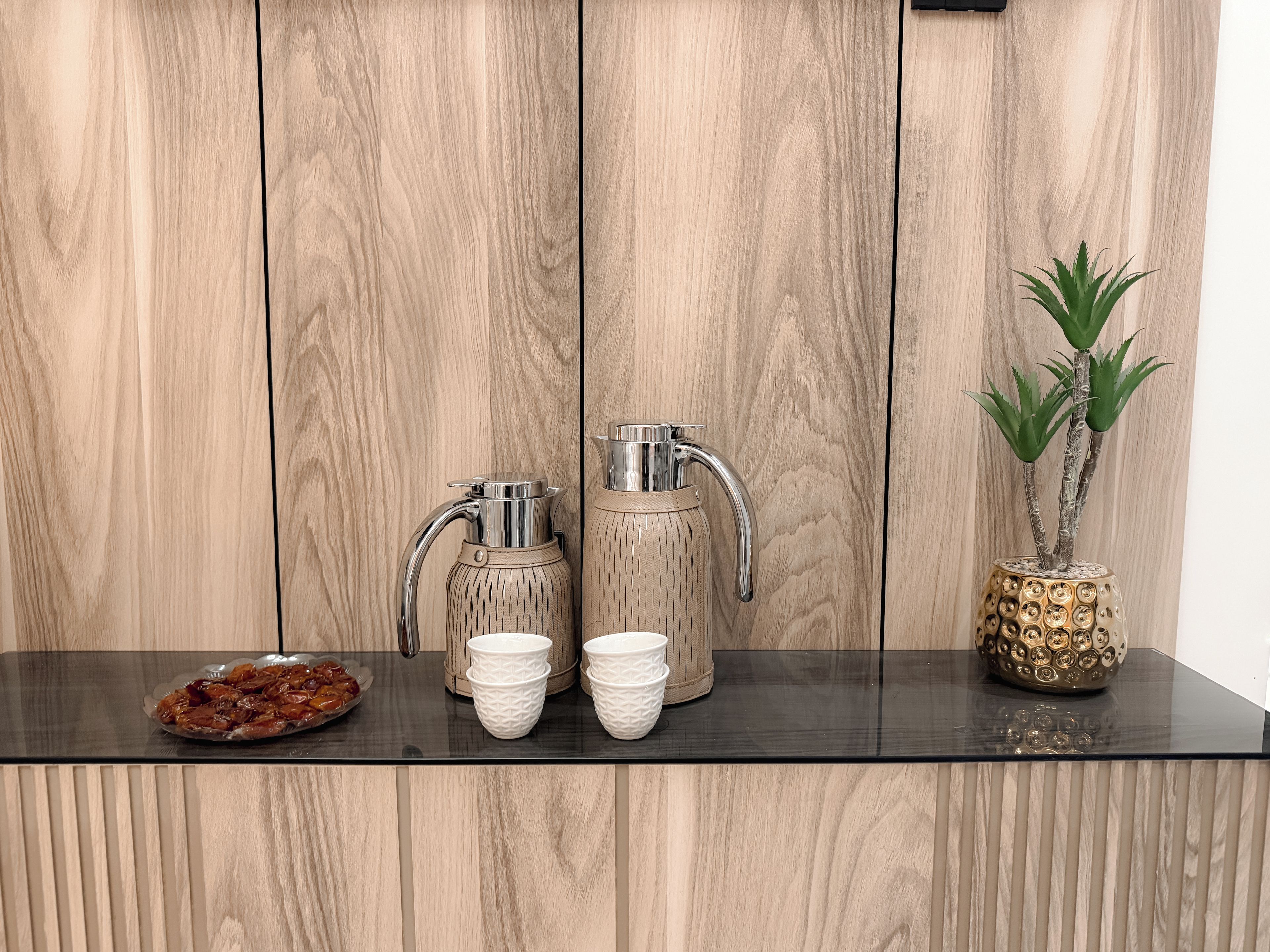 A kitchen counter with a coffee maker, a kettle, and a decorative plant.