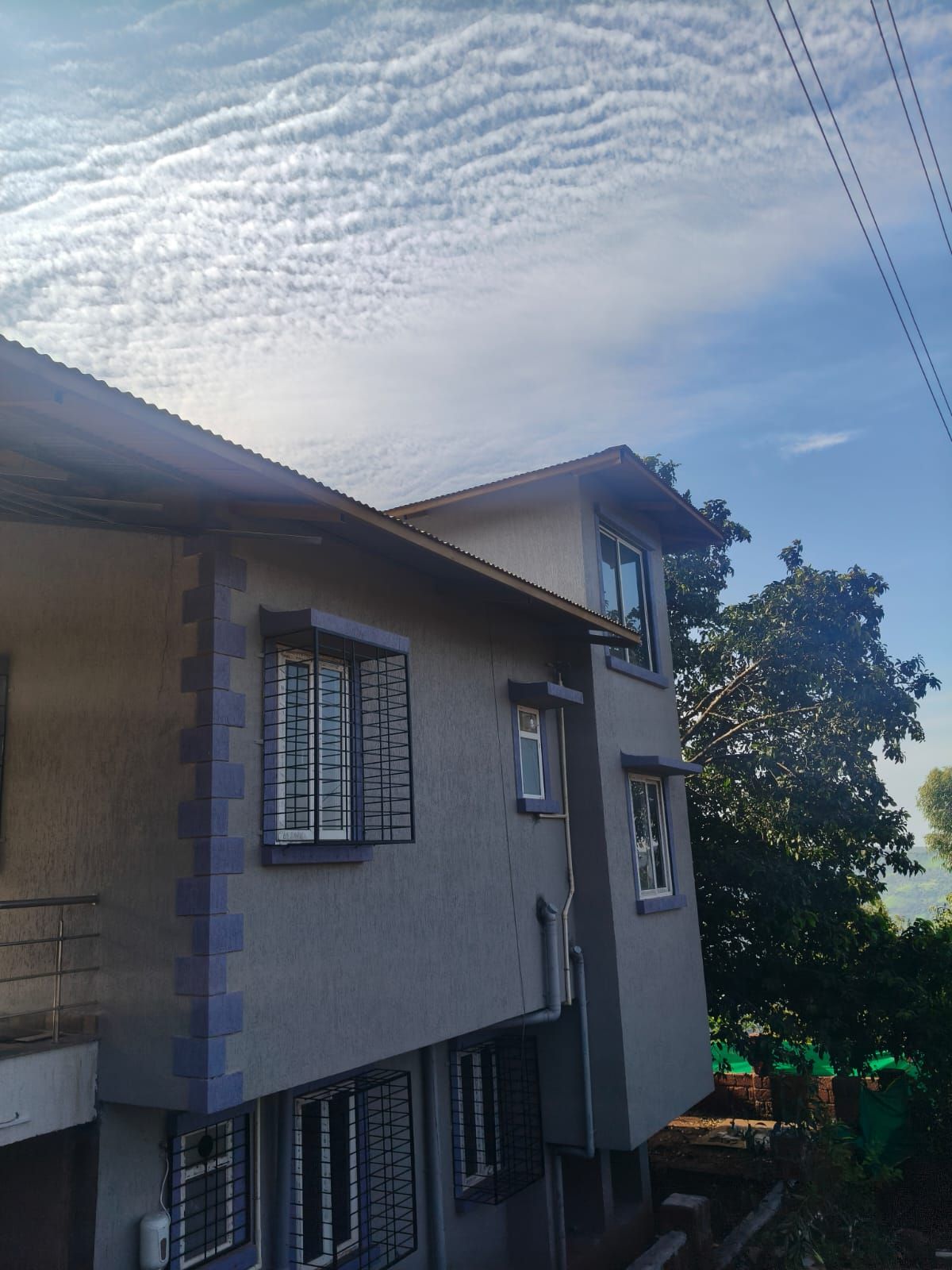 Un edificio de dos pisos con techo plano y una ventana con reja visible.