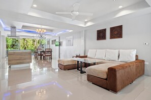 A modern living room with a sofa, a dining area, and a kitchen. - 10 bedroom & bath. 2 pools villas for 28 guests. (Tambon Kathu)
