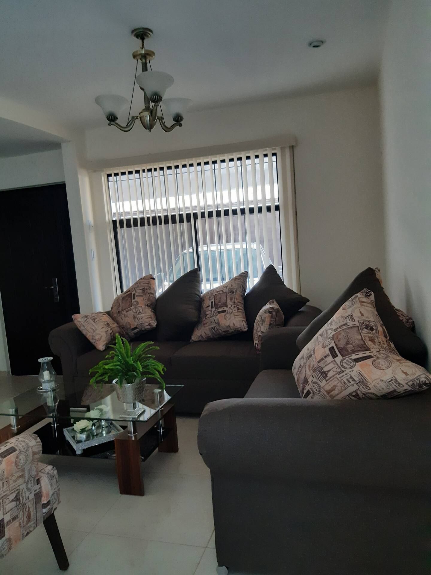 A living room with a sofa set, a coffee table with a plant, and a chandelier.