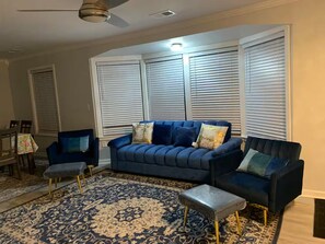 A living room with a blue sofa, two armchairs, a patterned rug, and a ceiling fan. - Mia's House (Radcliff)