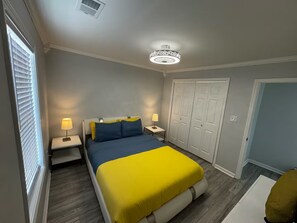 Een slaapkamer met een bed, nachtlampjes, een kledingkast en een plafondlamp.