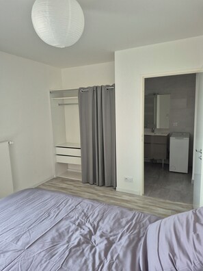 A bedroom with a bed, a wardrobe, a bathroom with a mirror, and a shower curtain. - Spacious 4-room apartment near Paris and Orly Airport (Châtenay-Malabry)