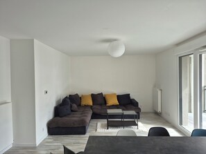 A modern living room with a sectional sofa, a glass coffee table, and a dining area. - Spacious 4-room apartment near Paris and Orly Airport (Châtenay-Malabry)