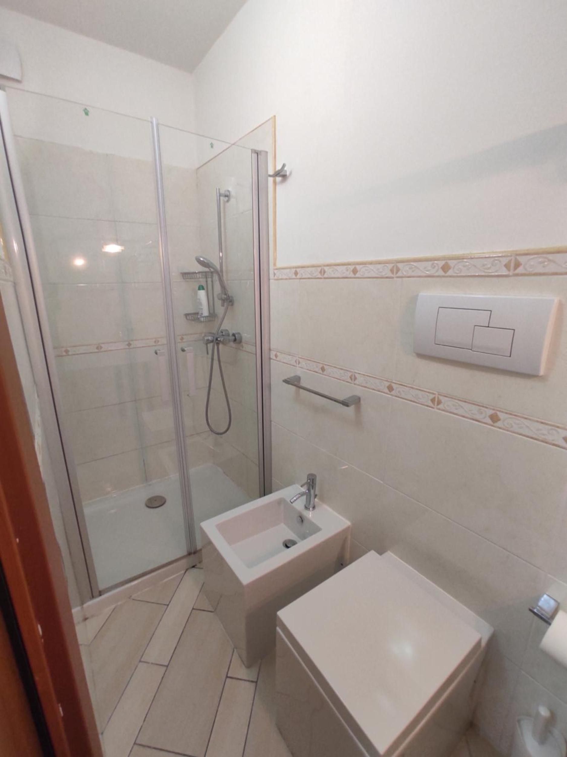 Un bagno con doccia vetrata, lavandino e water.