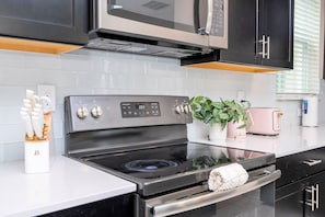 A modern kitchen with a black stove, white countertop, and a microwave above. - 5BR Championsgate Cinema, Themed Rooms, Pool (Kissimmee)