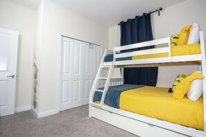 A bunk bed with yellow bedding, a white door with a Minion sticker, and a blue curtain. - 5BR Storey Lake Pool, Mickey & Minions Rooms (Kissimmee)