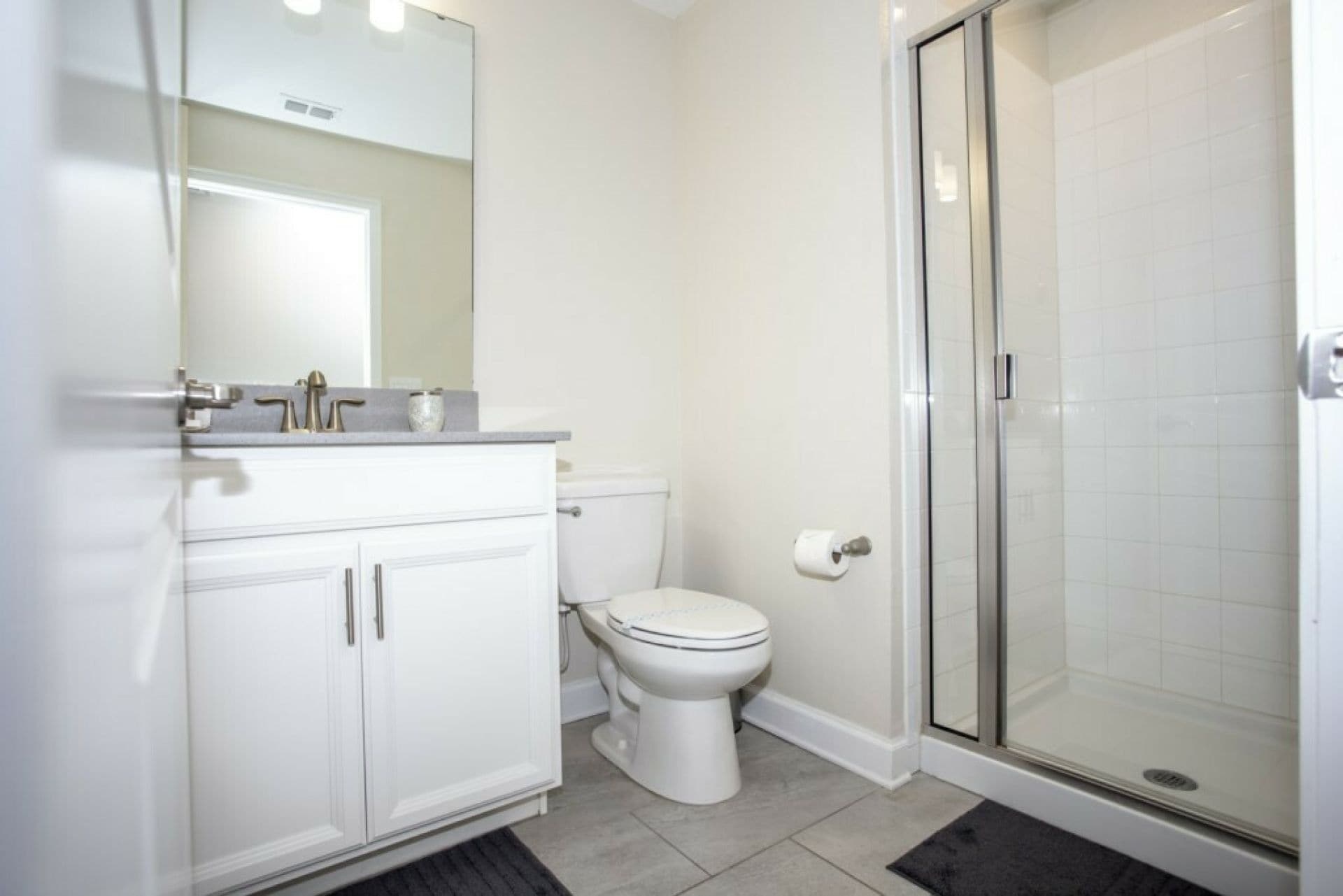 Un bagno con un WC, un lavandino con specchio e zona doccia.