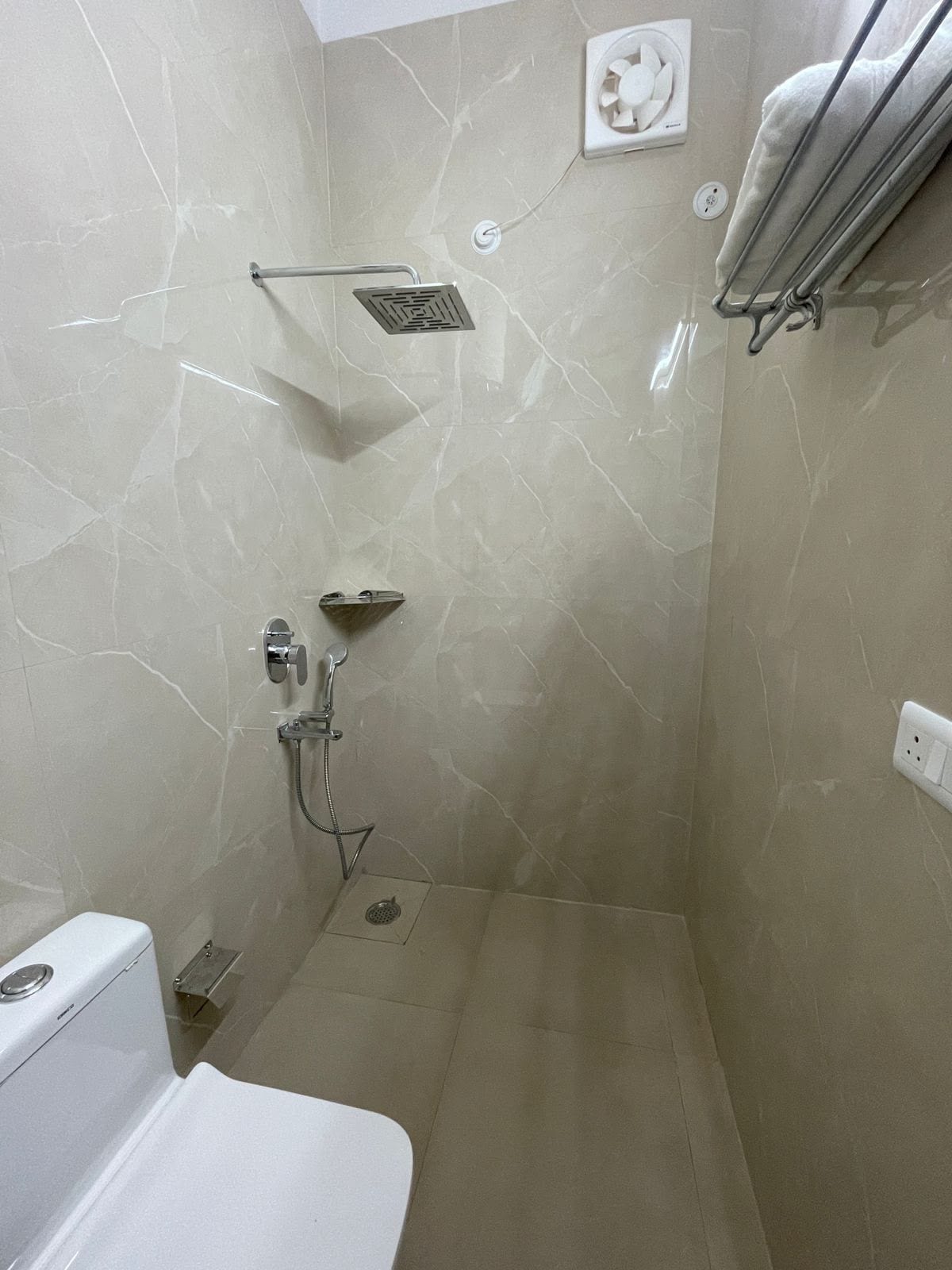 Un baño con ducha, inodoro y un perchero para toallas.