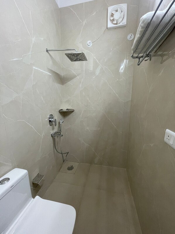 A bathroom with a shower, toilet, and a towel rack.